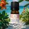 Bottle of Beach Vibes Essential Oil Blend standing in front of the words Hello Summer with tropical flowers and blurred ocean in background.